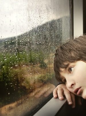 kid waiting by rainy window